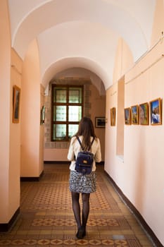 girl student standing in a hallway, rear view