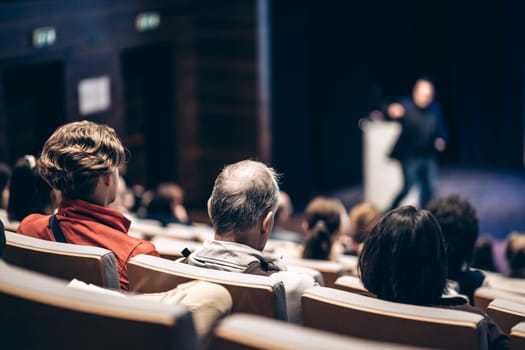 Speaker giving a talk in conference hall at business event. Rear view of unrecognizable people in audience at the conference hall. Business and entrepreneurship concept