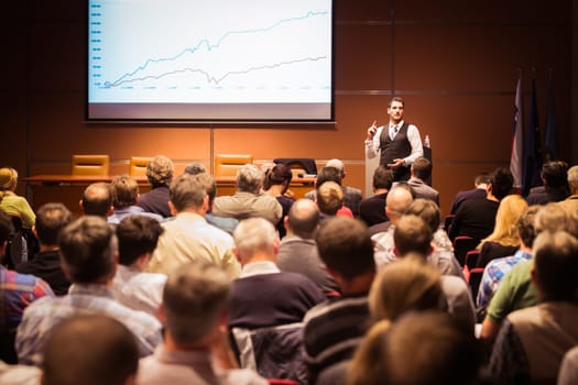 Speaker giving a talk in conference hall at business meeting event. Rear view of unrecognizable people in audience at the conference hall. Business and entrepreneurship concept.