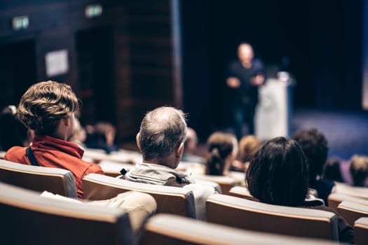 Speaker giving a talk in conference hall at business event. Rear view of unrecognizable people in audience at the conference hall. Business and entrepreneurship concept