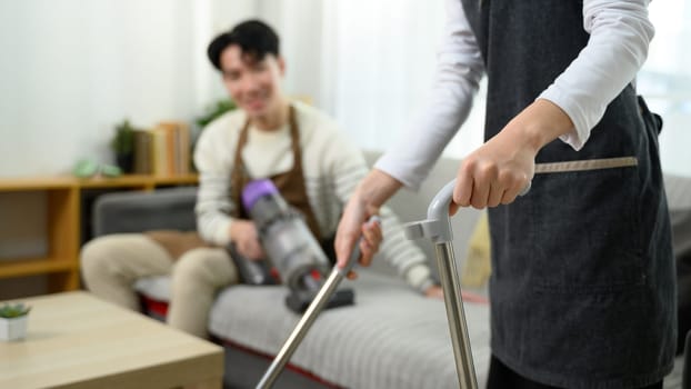 Happy asian couple enjoys tidying up their home on weekend.