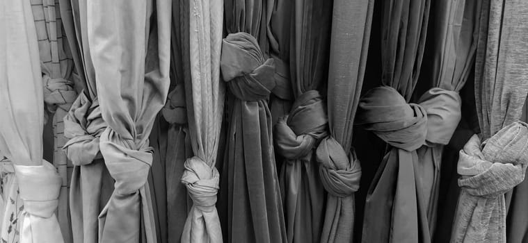 Curtain and fabric for drapery and interior decoration. Samples of fabrics in the store are hung vertically and tied in knots. Curtains in the showcase. Curtains monochrome black, gray and white color