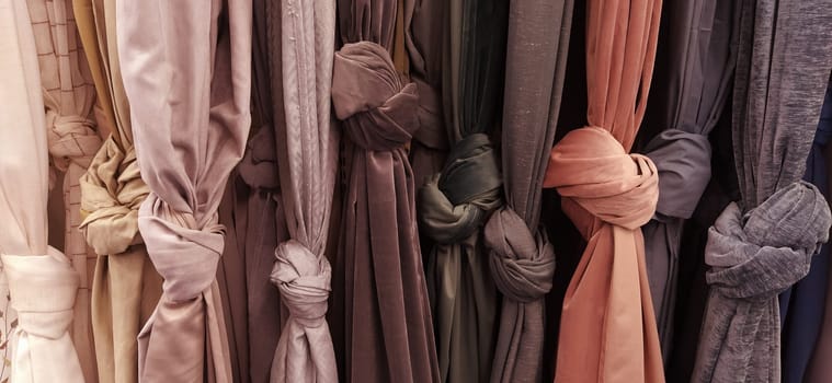 Curtain and fabric for drapery and interior decoration. Samples of fabrics in the store are hung vertically and tied in knots. Curtains in the showcase