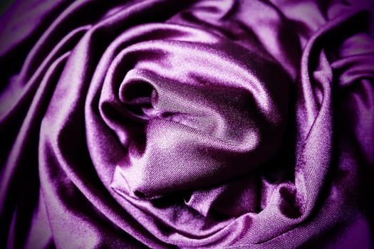 Velour fabric, similar to silk. Textiles in a folds, beautiful waves, twisted into a circle. Purple, pink, magenta shades on the drapery. Sewing material for dresses, furniture upholstery, curtains