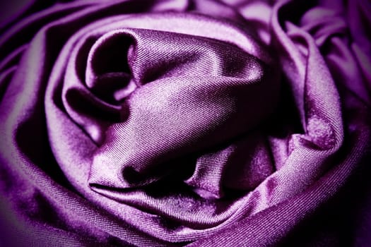 Velour fabric, similar to silk. Textiles in a folds, beautiful waves, twisted into a circle. Purple, pink, magenta shades on the drapery. Sewing material for dresses, furniture upholstery, curtains