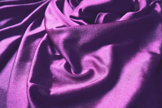 Velour fabric, similar to silk. Textiles in a folds and beautiful waves. Purple, pink, magenta shades on the drapery. Sewing material for evening dresses, furniture upholstery, curtains and interior