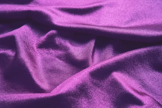 Velour fabric, similar to silk. Textiles in a folds and beautiful waves. Purple, pink, magenta shades on the drapery. Sewing material for evening dresses, furniture upholstery, curtains and interior