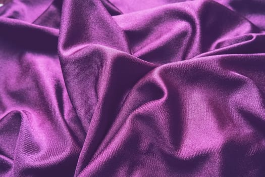 Velour fabric, similar to silk. Textiles in a folds and beautiful waves. Purple, pink, magenta shades on the drapery. Sewing material for evening dresses, furniture upholstery, curtains and interior