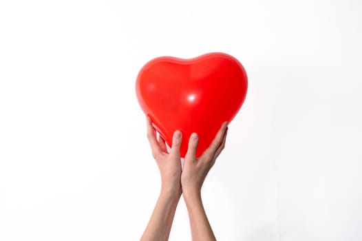 Hands holding a red heart shaped balloon against white background