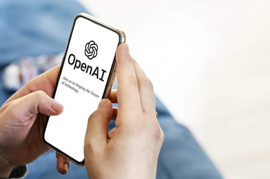 San Francisco US, Dec 2022: Female hands holding a phone with the OpenAI webpage on the screen. Interior shot. OpenAI is a non-profit artificial intelligence research organization. Technology concept