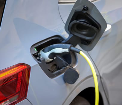 An electric car is charged at a charging station using a charging cable.