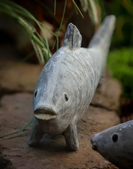 The sculpture, figure of a fish on the edge of my goldfish pond.