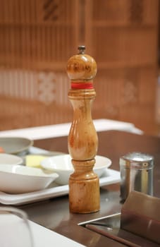 A salt or pepper mill is ready next to the stove in the kitchen.