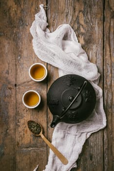 Traditional japanese herbal tea recipe prepared in cast iron teapot with organic dry herbs. Top view of asian traditional hot beverage on wooden table.