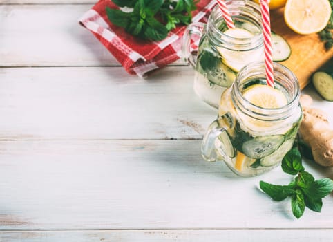 Homemade detox lemonade with cucumber, ginger and mint in retro mason jar glass on wooden table from above. Summer refreshment drink recipe. Healthy eating concept.