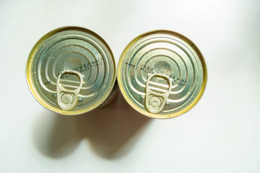 Two dirty cans with food and an opener, top view