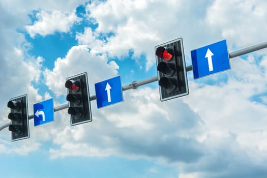 Traffic lights with a red light against the cloudy sky