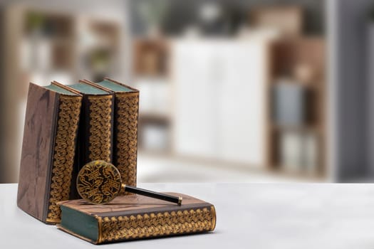 Ancient books with a magnifying glass on a bright table isolated over abstract blurred library, study room or office. University, history, memory and knowledge concept.