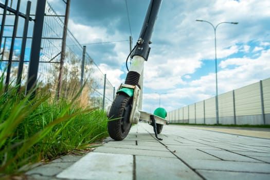 Single electric scooter stands on the pavement next to the street
