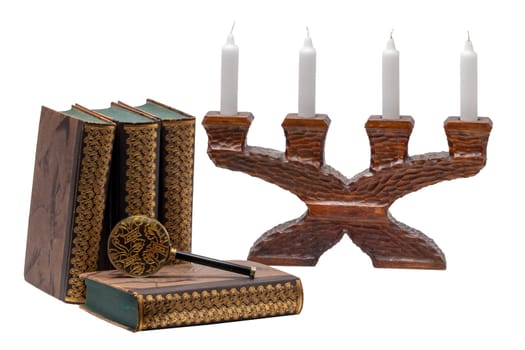 Ancient books with a magnifying glass and a antique wooden candle holder isolated on a white background. Clipping path. Education concept.