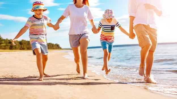 Family with holding hands running along seacoast. Concept of the family vacation and tourism.