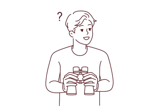 Smiling young man feeling confused holding binoculars in hands. Happy male frustrated looking in binocular finding solution. Exploration and discovery.
