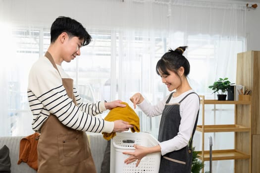 Happy asian couple enjoys tidying up their home on weekend.
