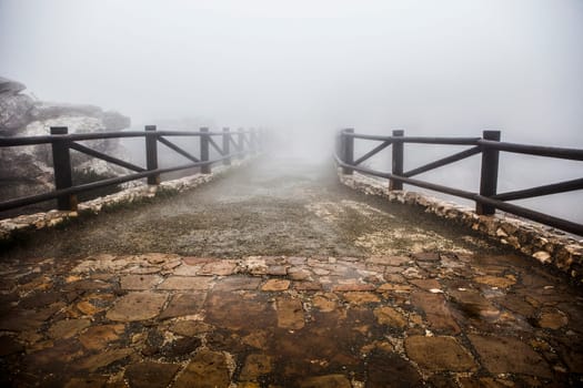 Wooden walkway lost in the fog. Torcal De Antequera, Malaga, Spain