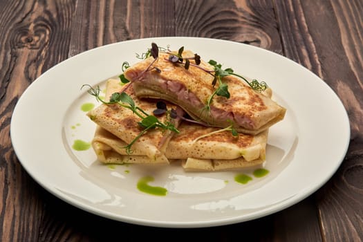 Delicious juicy pancakes with ham on a white plate. High quality photo