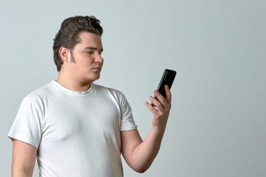 a man on a light background looks at the phone. High quality photo