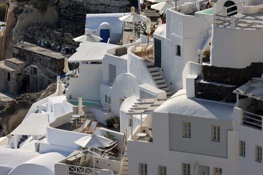 Oia, Santorini, Greece - June 28, 2021: Whitewashed houses with terraces and pools and a beautiful view in Oia on Santorini island, Greece