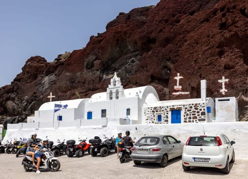 Santorini, Greece - July 01, 2021: Greek church built into the mountain located near the famous Red Beach of Akrotiri. Santorini Island, Greece