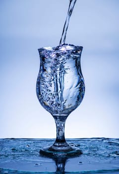 The image of pouring drinking water, into a glass, that makes one feel refreshed on blurred white background, Splashing water, Sparkling water