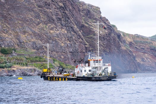 Madeira / Portugal - July 15, 2021. The industrial ship with workers moored at Madeira coast.