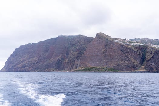 View of sheer volcanic cliff rising above ocean.