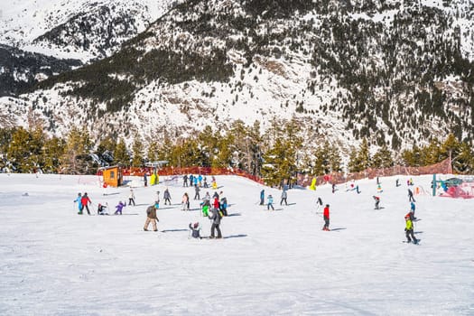 People, families and kids having fun and learning how to ski and snowboard on El Tarter green slops. Winter ski holidays in Andorra Pyrenees Mountains