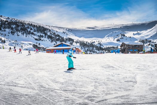 Woman, beginner snowboarder learning how to ride on a snowboard. Winter ski holidays in El Tarter, Grandvalira, Andorra, Pyrenees Mountains