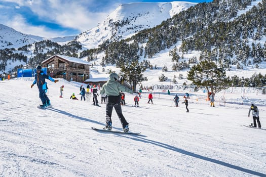 Instructor or trainer teaching how to snowboard in El Tarter green area. Winter ski holidays in Andorra, Grandvalira, Pyrenees Mountains