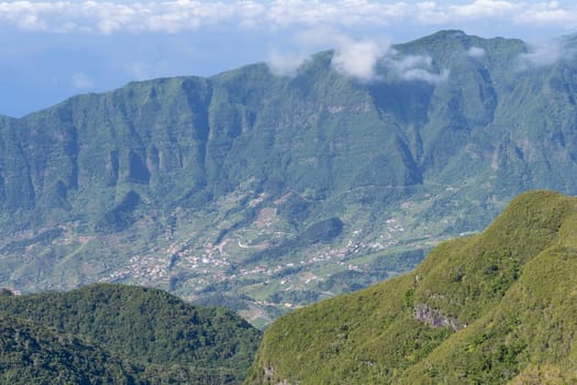 Aerial view on small city, huge mountains on background. Madeira island, Portugal.