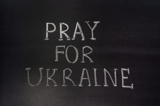 Words "Pray for Ukraine"" writed on blackboard with chalk"