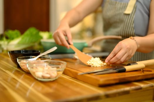 Cropped shot of woman preparing fresh ingredients on a rustic wooden countertop.