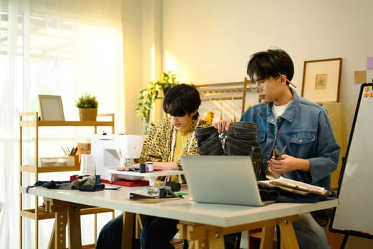 Young fashion designers collaborating on new project in a studio.