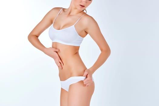 Young, slim, healthy and beautiful woman in white lingerie isolated on the white background