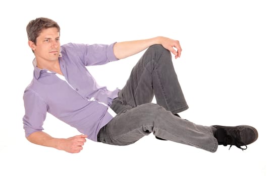 A young handsome man in jeans and a checkered shirt sitting on the floor, looking.away, isolated for white background..