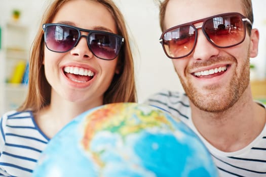 Happy dates looking at camera through sunglasses with toothy smiles