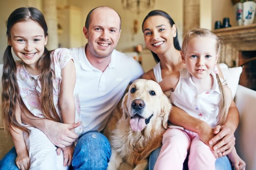 Cute siblings sitting on knees of their parents with dog near by