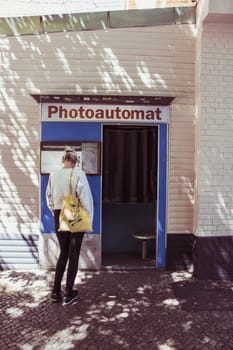 Berlin, Germany, June 2022: Woman checking out a photoautomat, vintage and retro photo booth