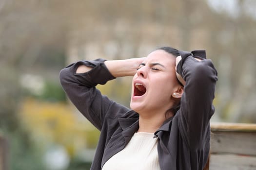 Desperate woman yelling alone standing in a park