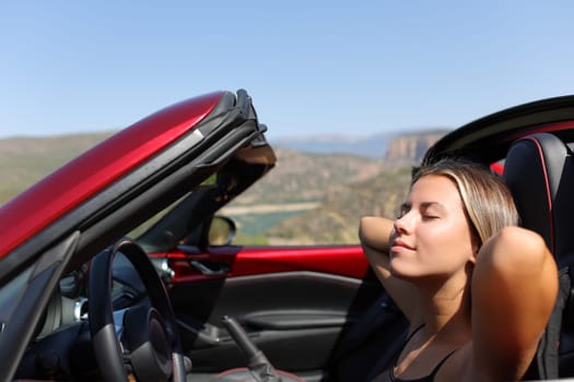 Woman relaxing in a convertible car in nature