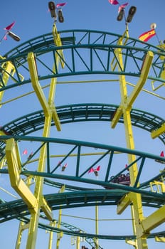 Roller coaster circles structure. Funfair attraction over blue sky seen from ground